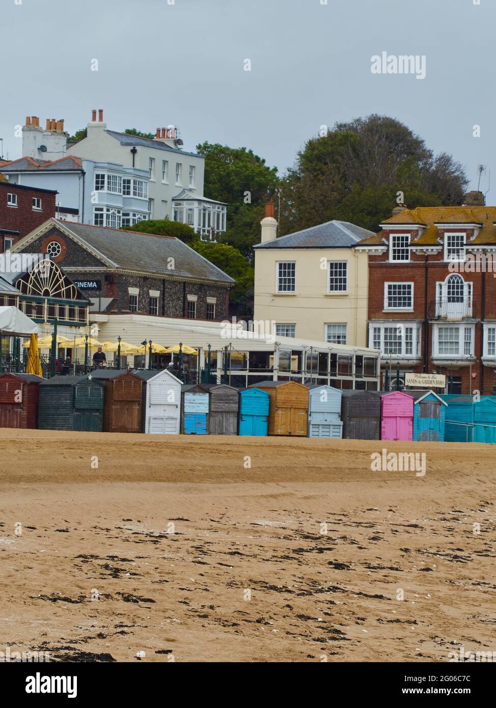 The beach, beach huts and buildings of a seaside town - specifically Broadstairs. A heavy sky hangs overhead, perhaps why the beach is deserted. Stock Photo
