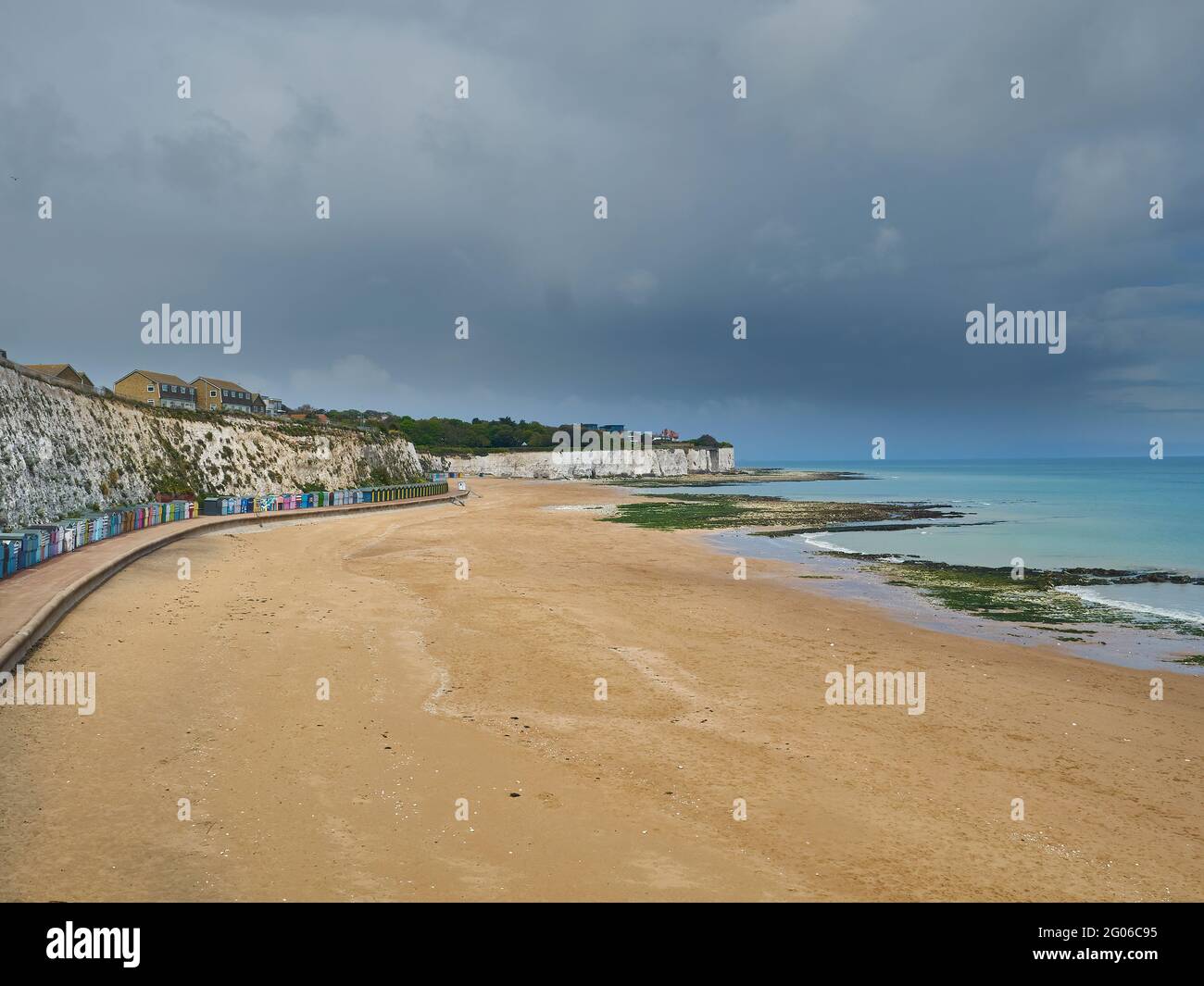 Stone Bay’s sweeping curve, with its cliffs, beach huts and golden sands, empty for now but ready for summer (once the looming rain clouds clear!). Stock Photo