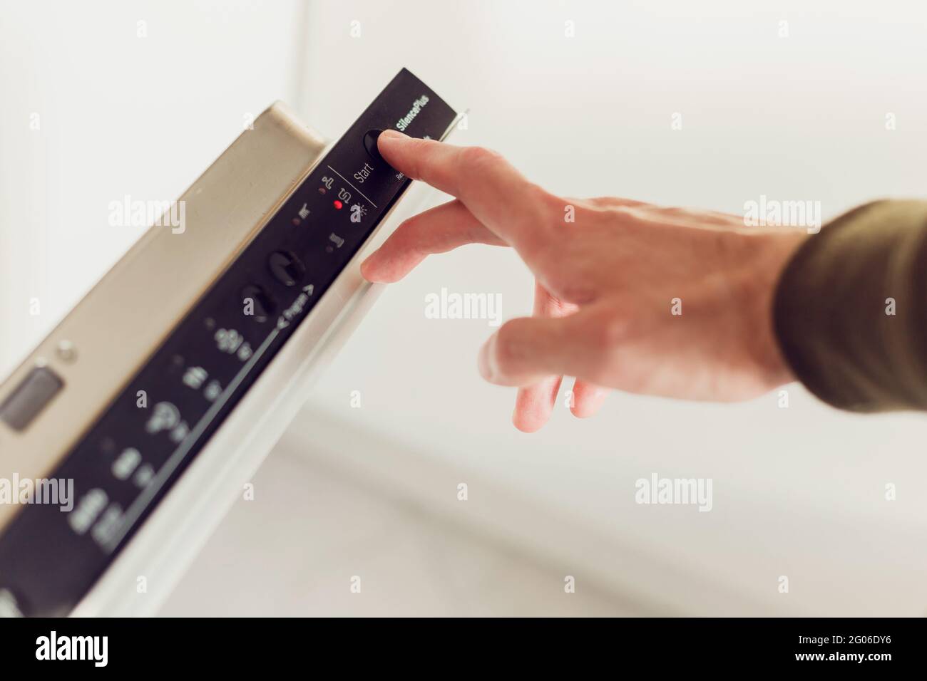 Man pushing start button on the control panel of the dishwasher Stock