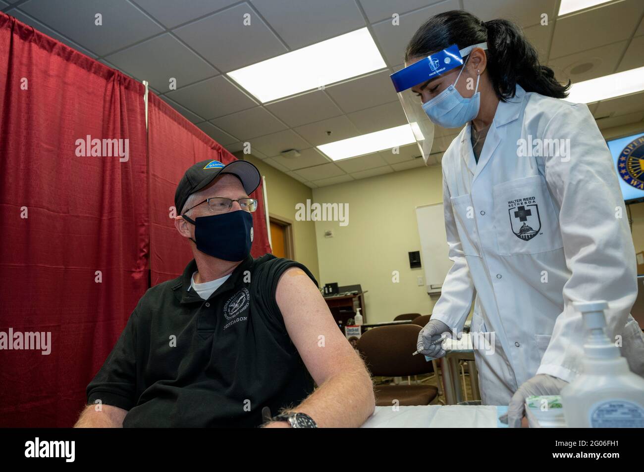 Reportage:  Acting Defense Secretary Chris Miller talks with Navy Hospitalman Samantha Alvarez, after she administered a COVID-19 vaccine to him, Walter Reed National Military Medical Center, Bethesda, Md., Dec. 14, 2020. Stock Photo