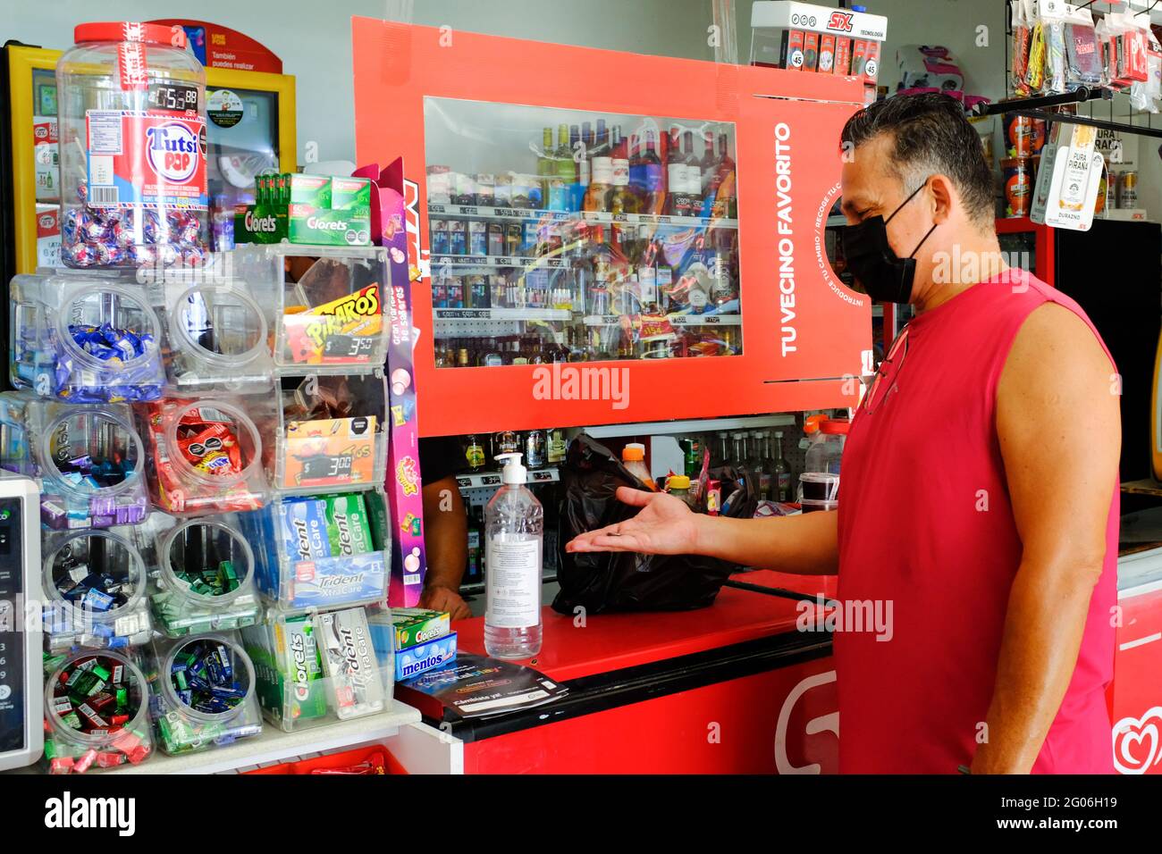 Man buying supplies in a little shop in Merida Mexico during the Covid-19 Pandemic / One can observe the precautionary measures taken by the store (plastic separator and sanitizing gel) Stock Photo