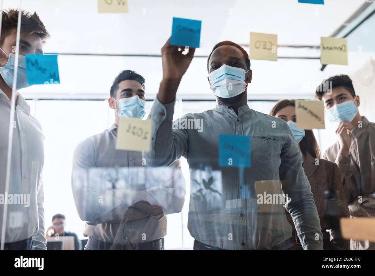 Colleagues in face masks having meeting using sticky notes Stock Photo