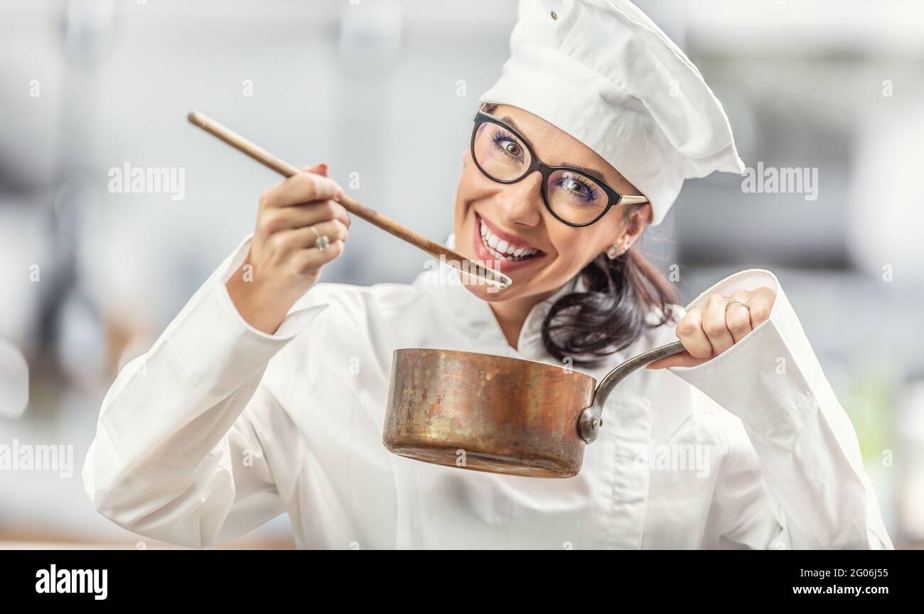 https://c8.alamy.com/comp/2G06J55/smiling-female-chef-in-professional-outfit-tastes-food-from-wooden-spoon-holding-a-copper-pot-2G06J55.jpg