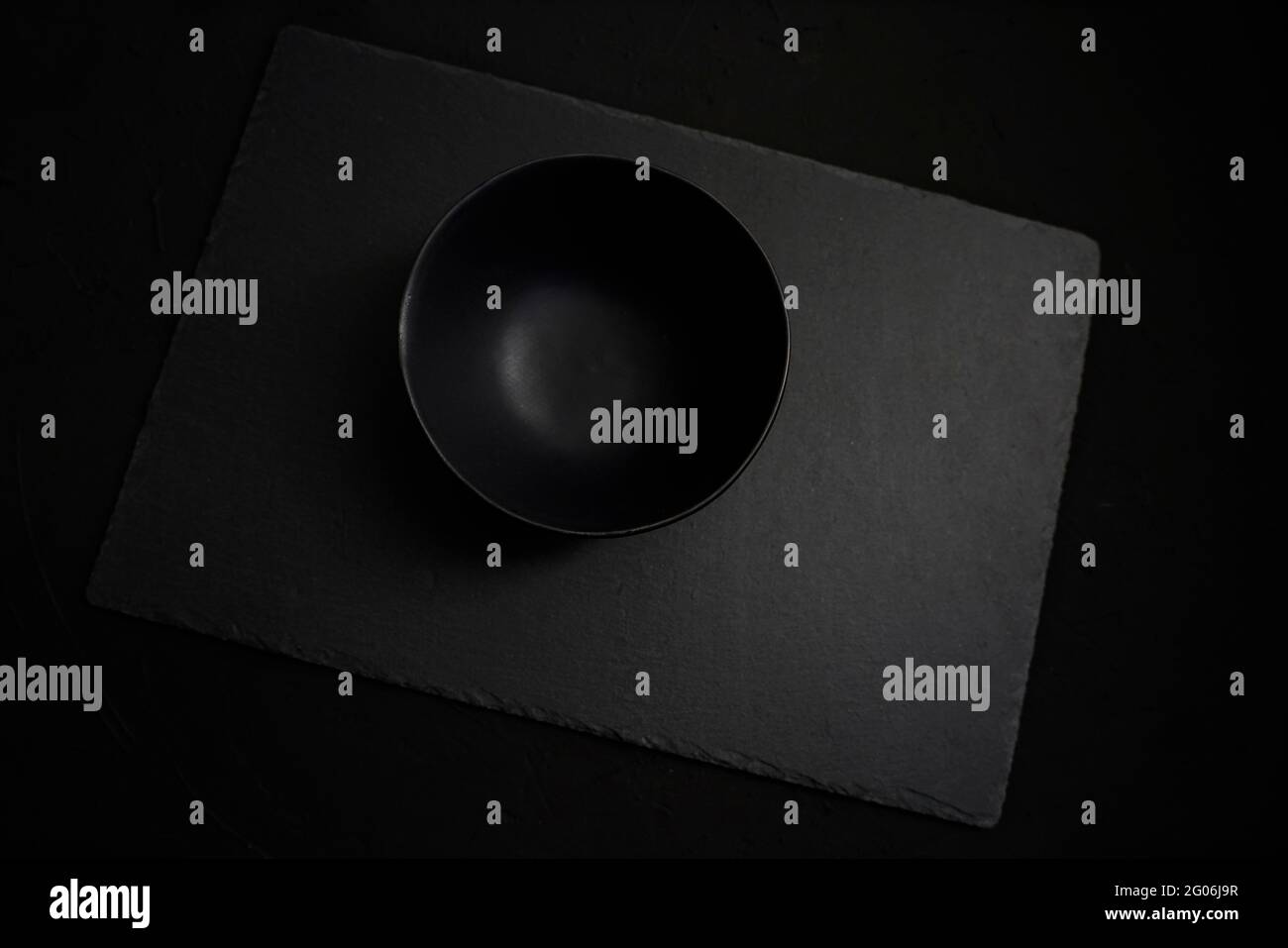 Empty black ceramic bowl over a dark slate background Stock Photo