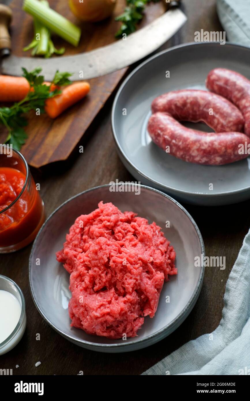 Ingredients for the preparation of meat bolognese ragout, ground beef, pork, thick tomato sauce, white onion, celery, carrots, milk, extra virgin oliv Stock Photo