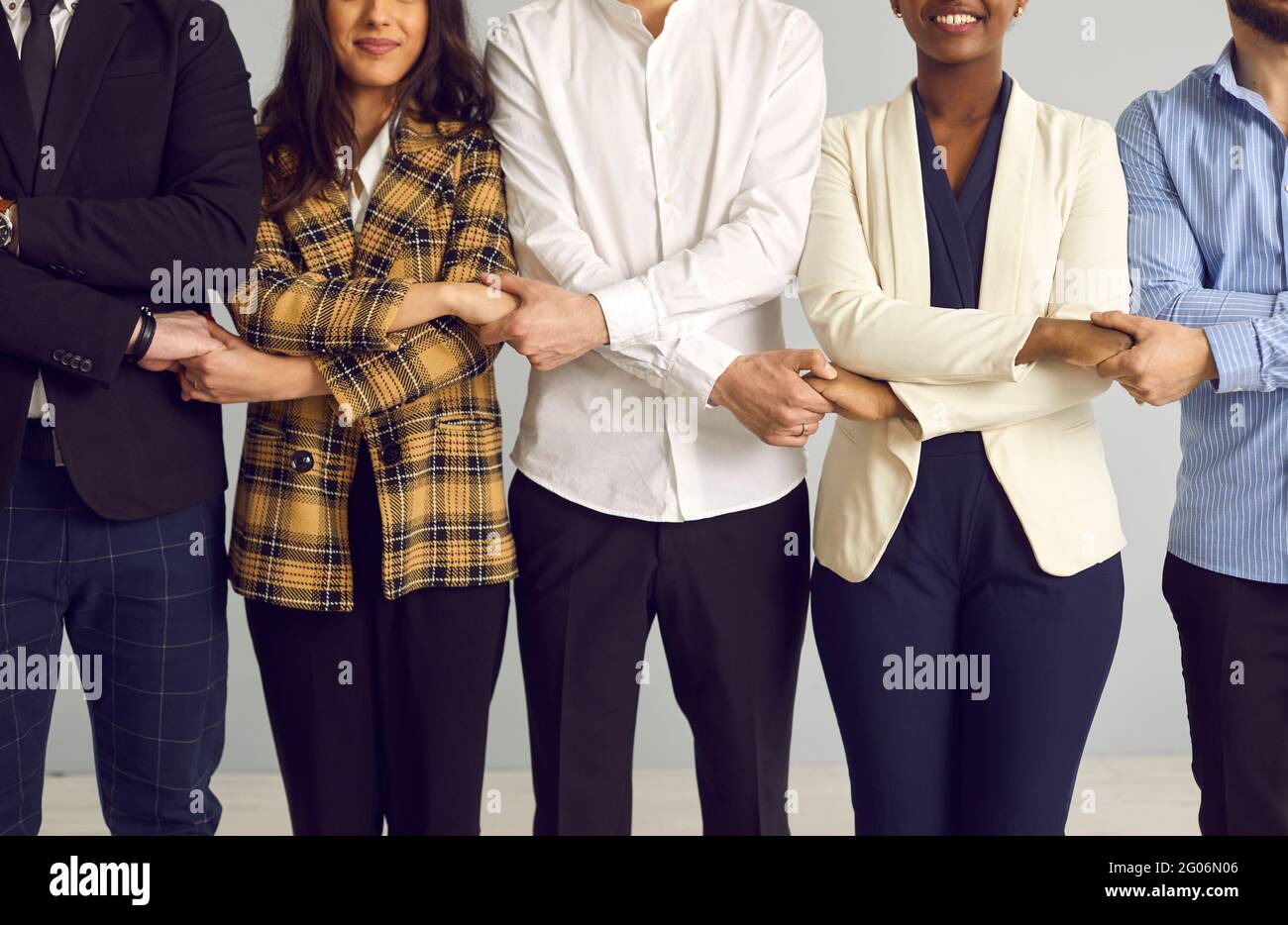 Business team standing in line holding hands together midsection studio shot Stock Photo