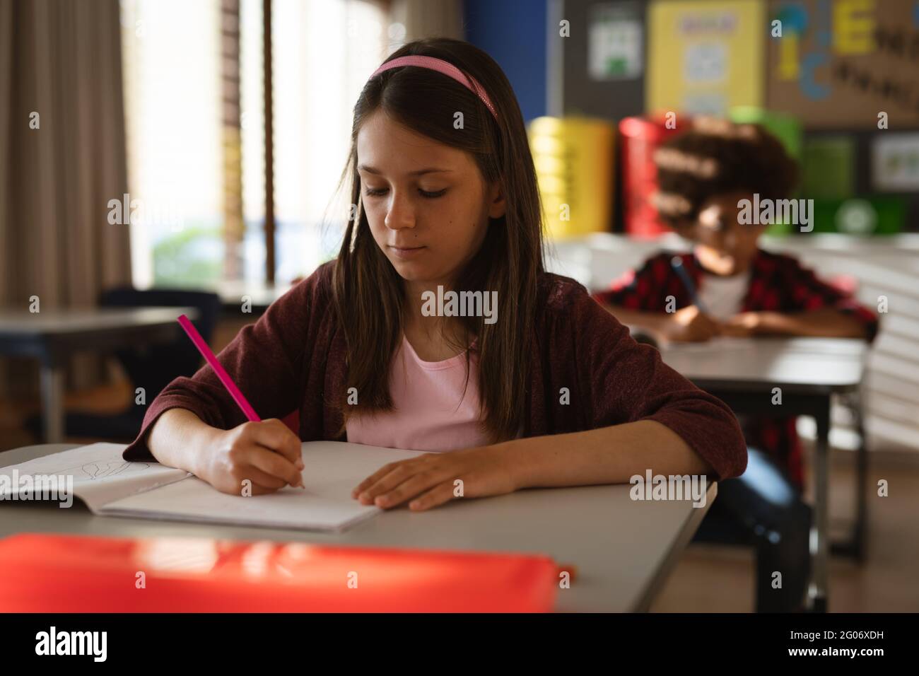 Caucasian girl studying while siting on his desk in class at elementary school Stock Photo