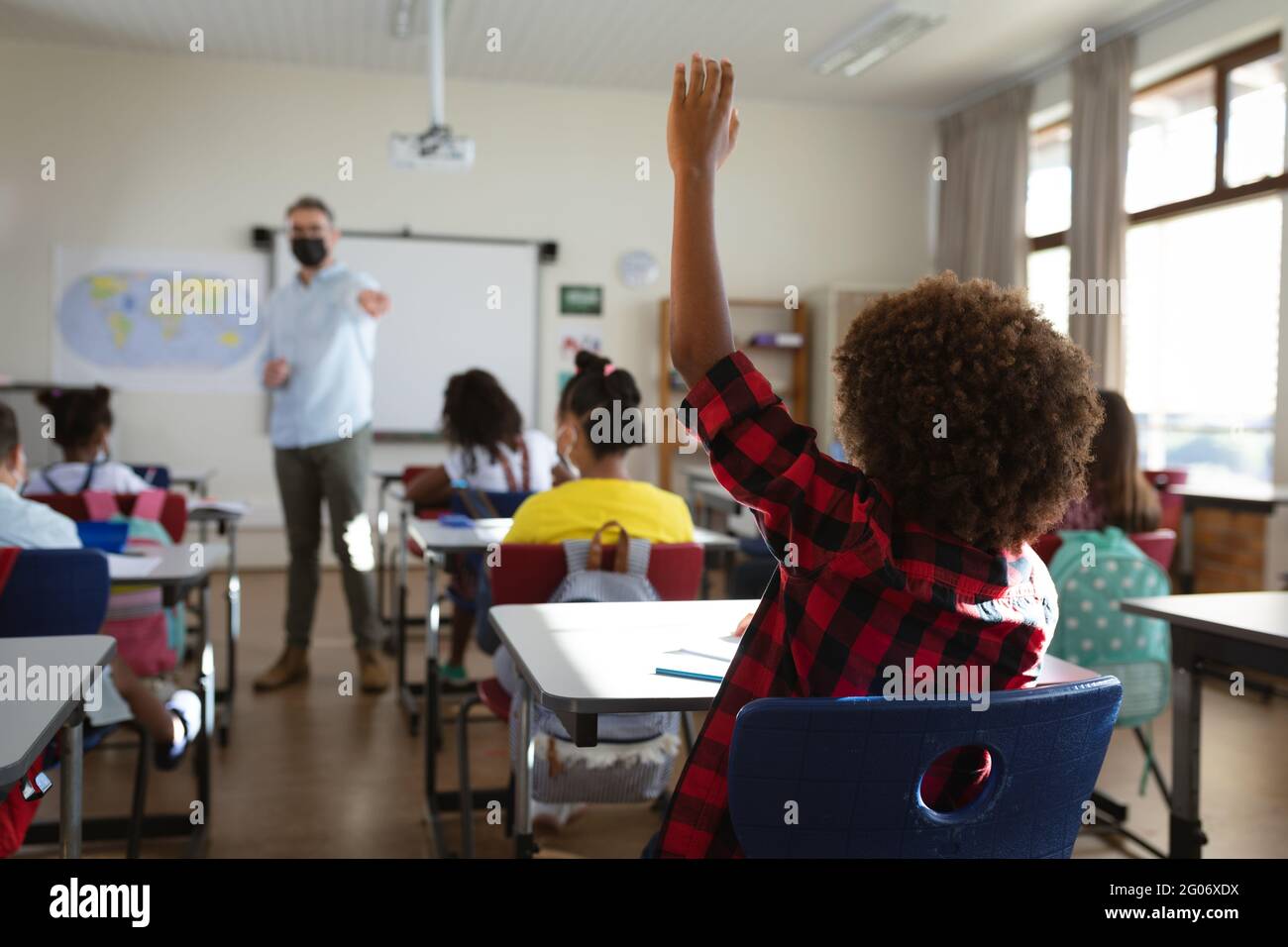 Rear view of african american boy raising his hand while sitting on his ...