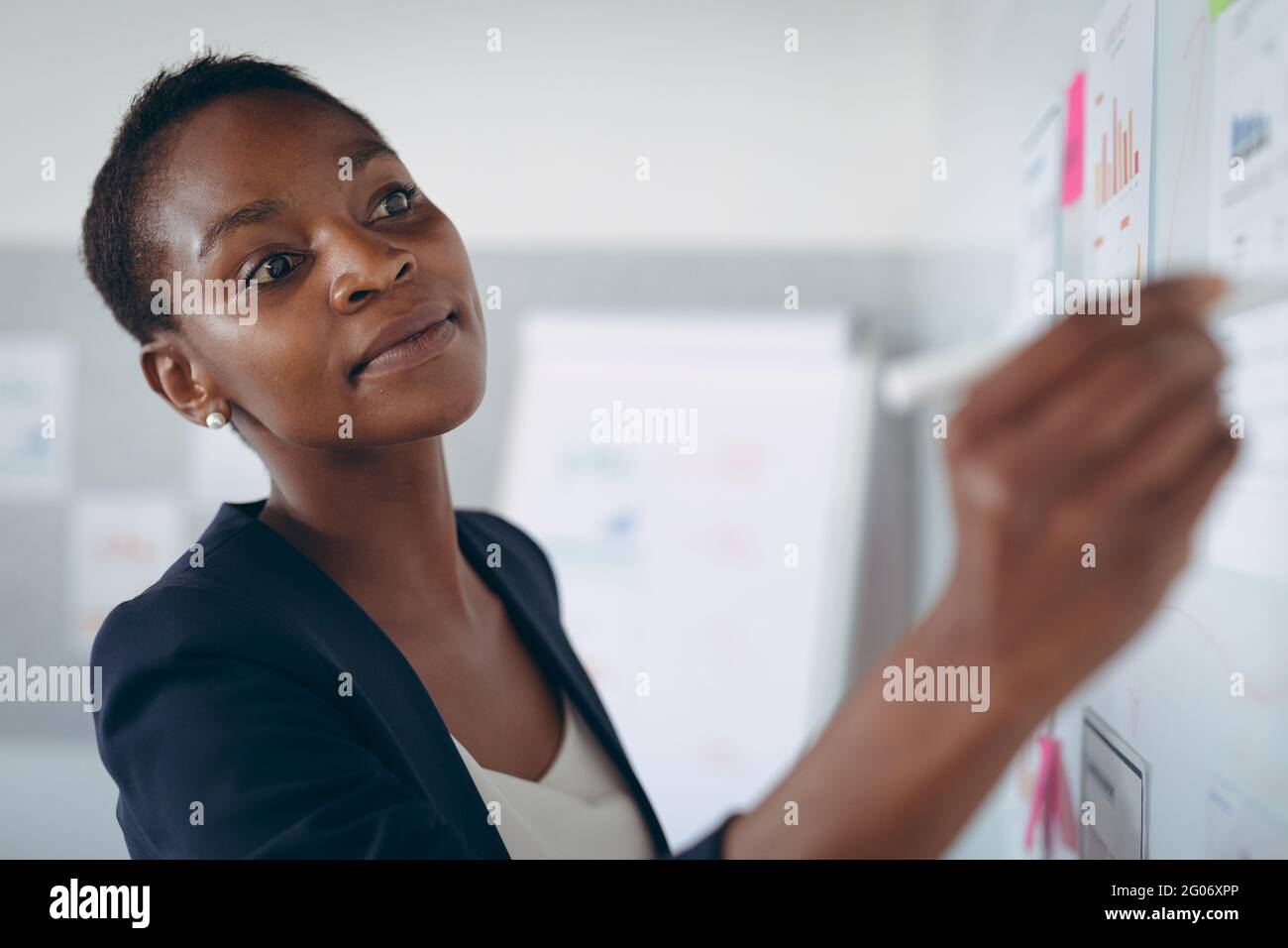 African american businesswoman making notes and adding post-ins on wall Stock Photo