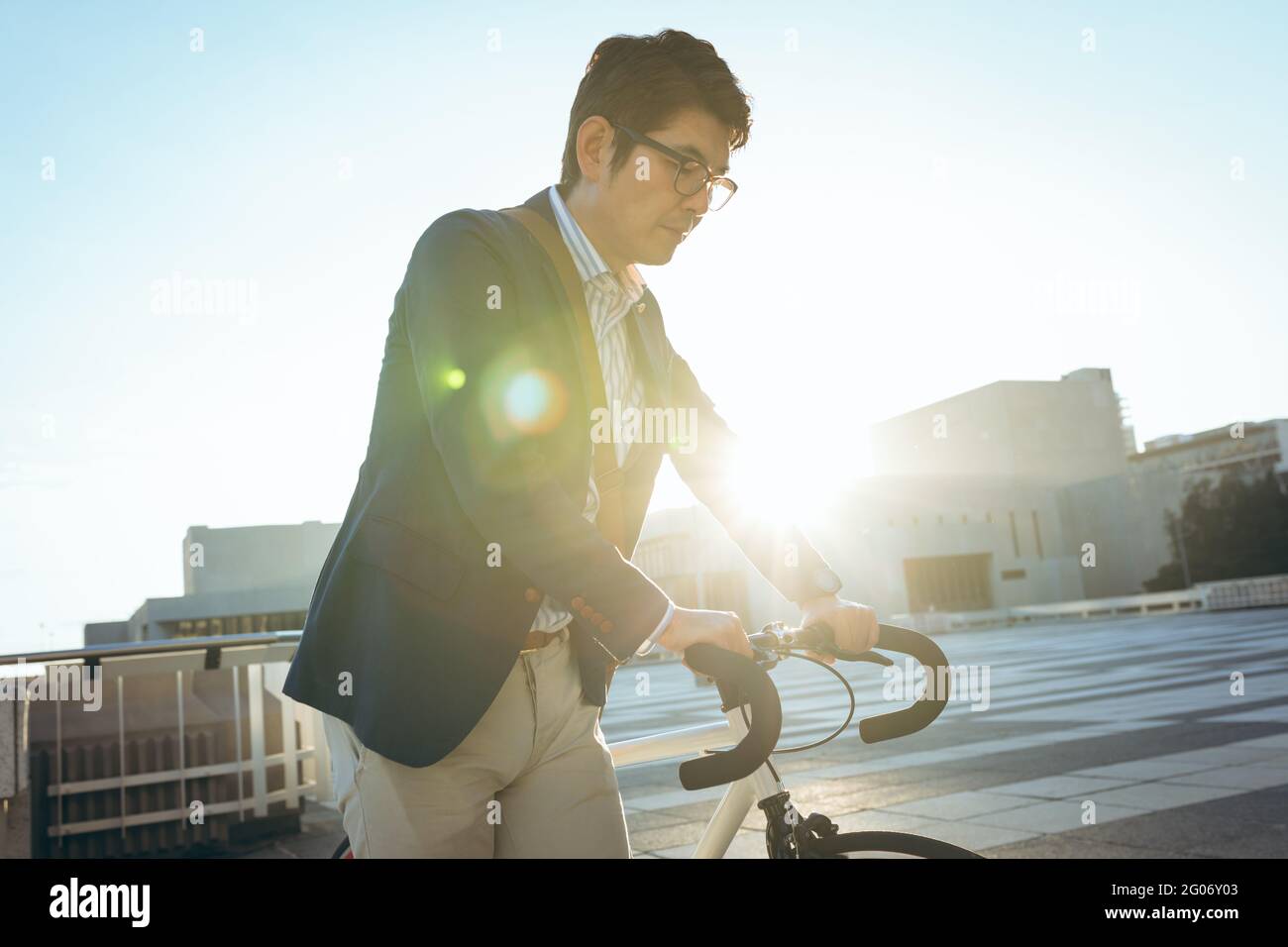 Midsection of asian businessman walking with bike in city street Stock Photo