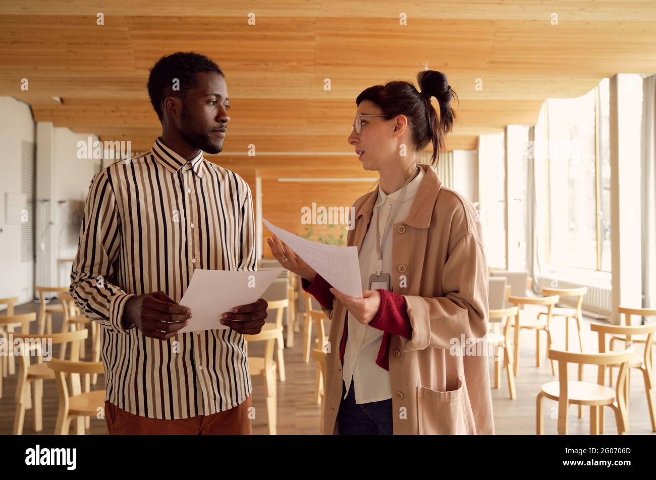 Two young business people discussing documents together at office Stock Photo