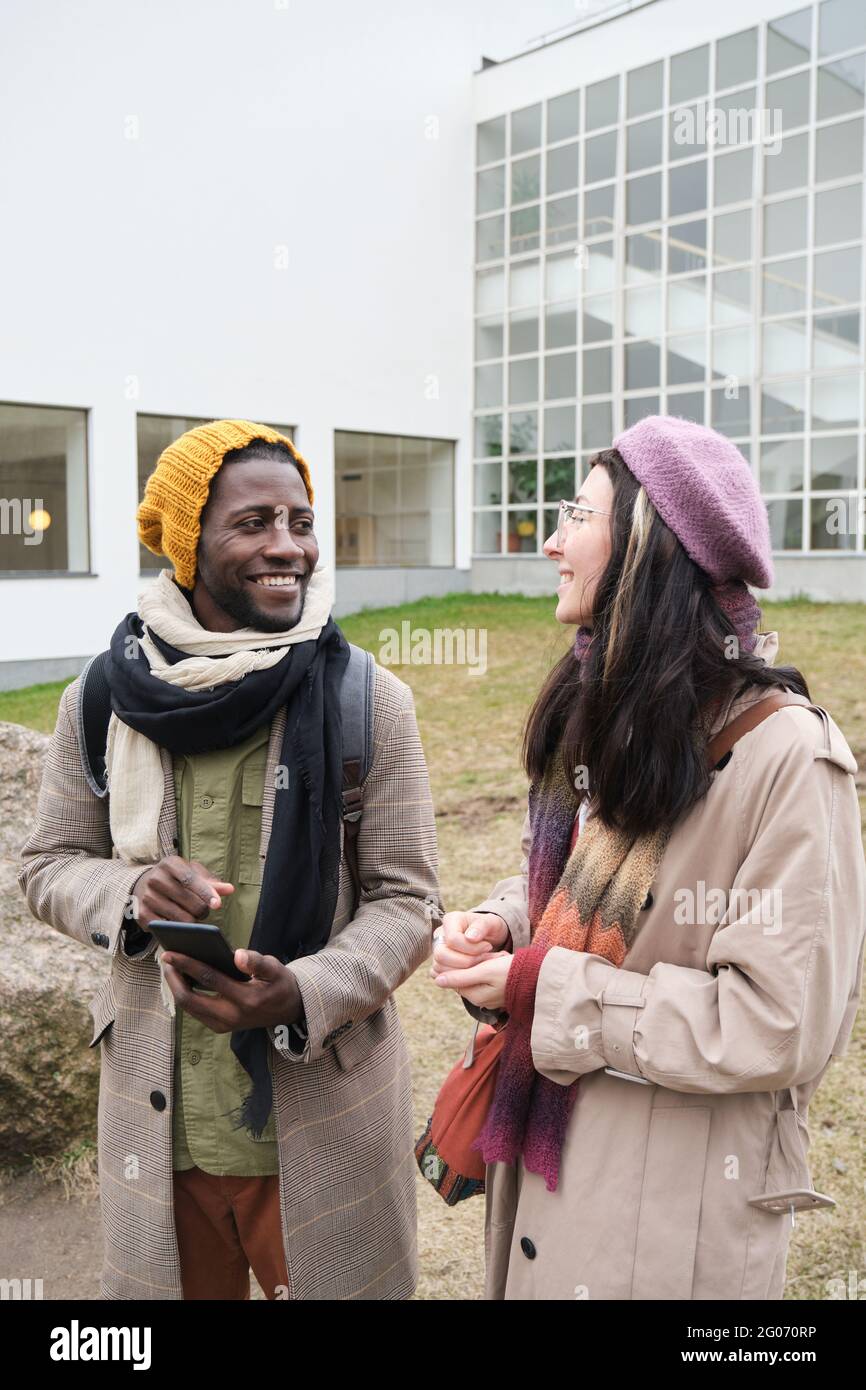 Two young friends talking and smiling while walking in the city Stock Photo