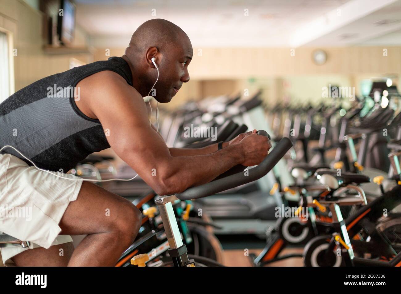 Athletic black man doing cardio workout on exercise bike in gym