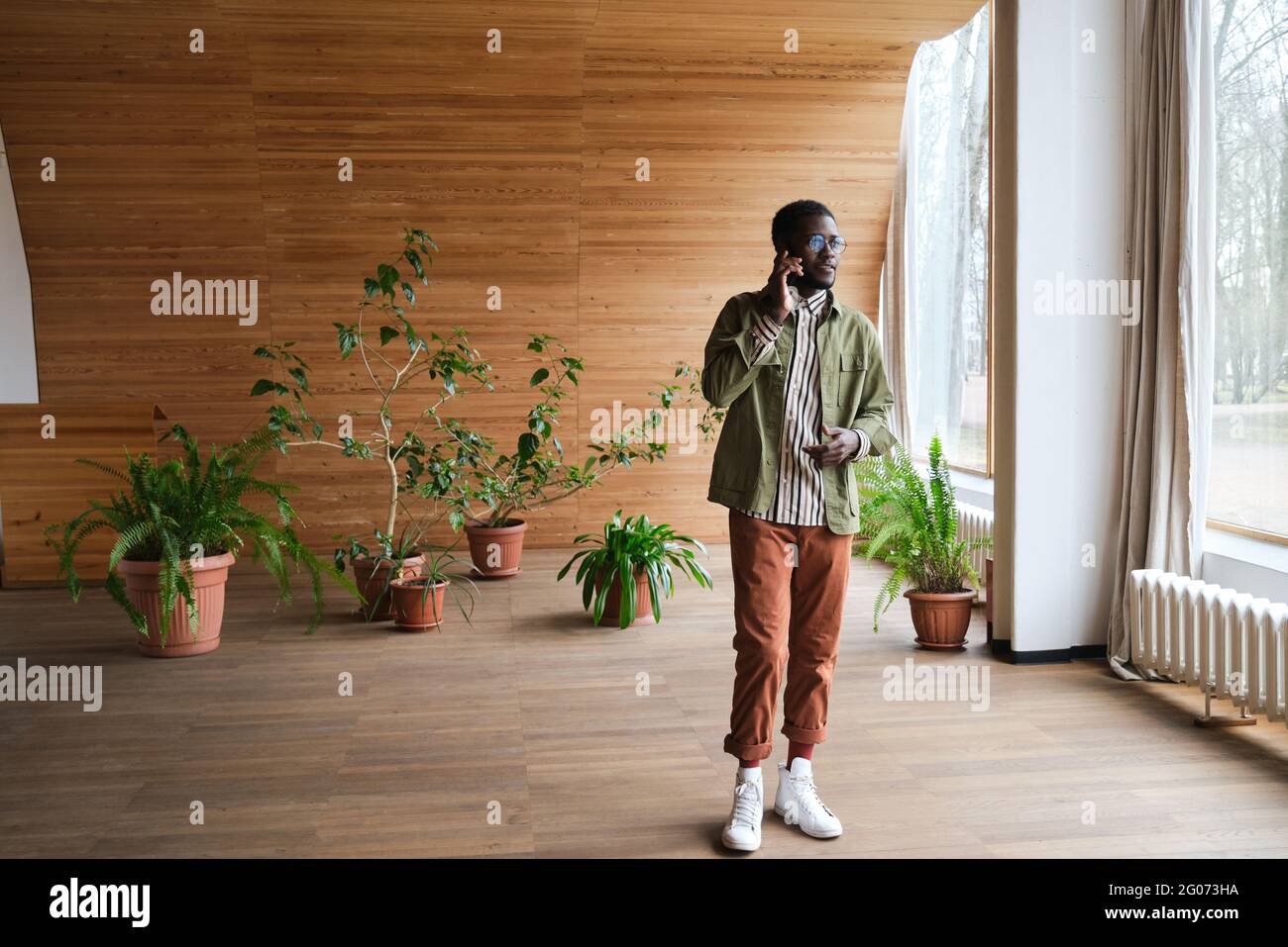 African young man talking on mobile phone while standing at modern office hall Stock Photo