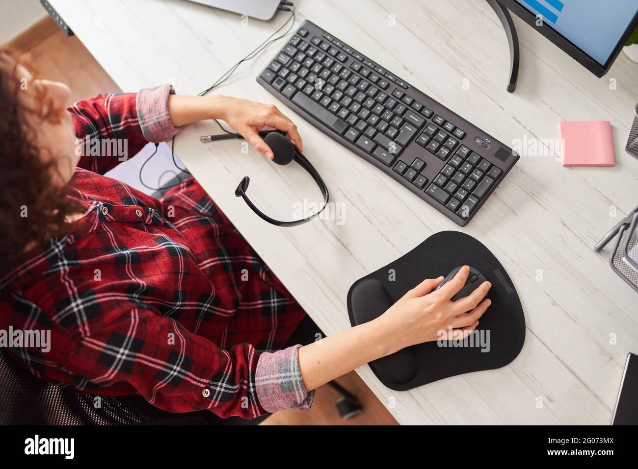Top view of a woman's hands using the computer mouse and holding a headset Stock Photo