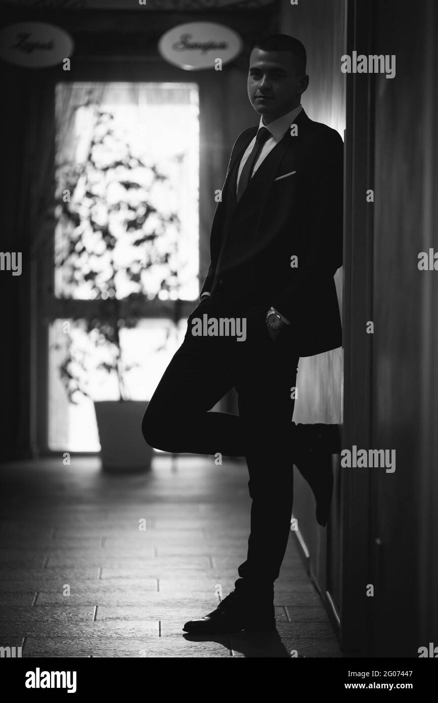 Young man in an elegant black suit with a tie posing Stock Photo - Alamy
