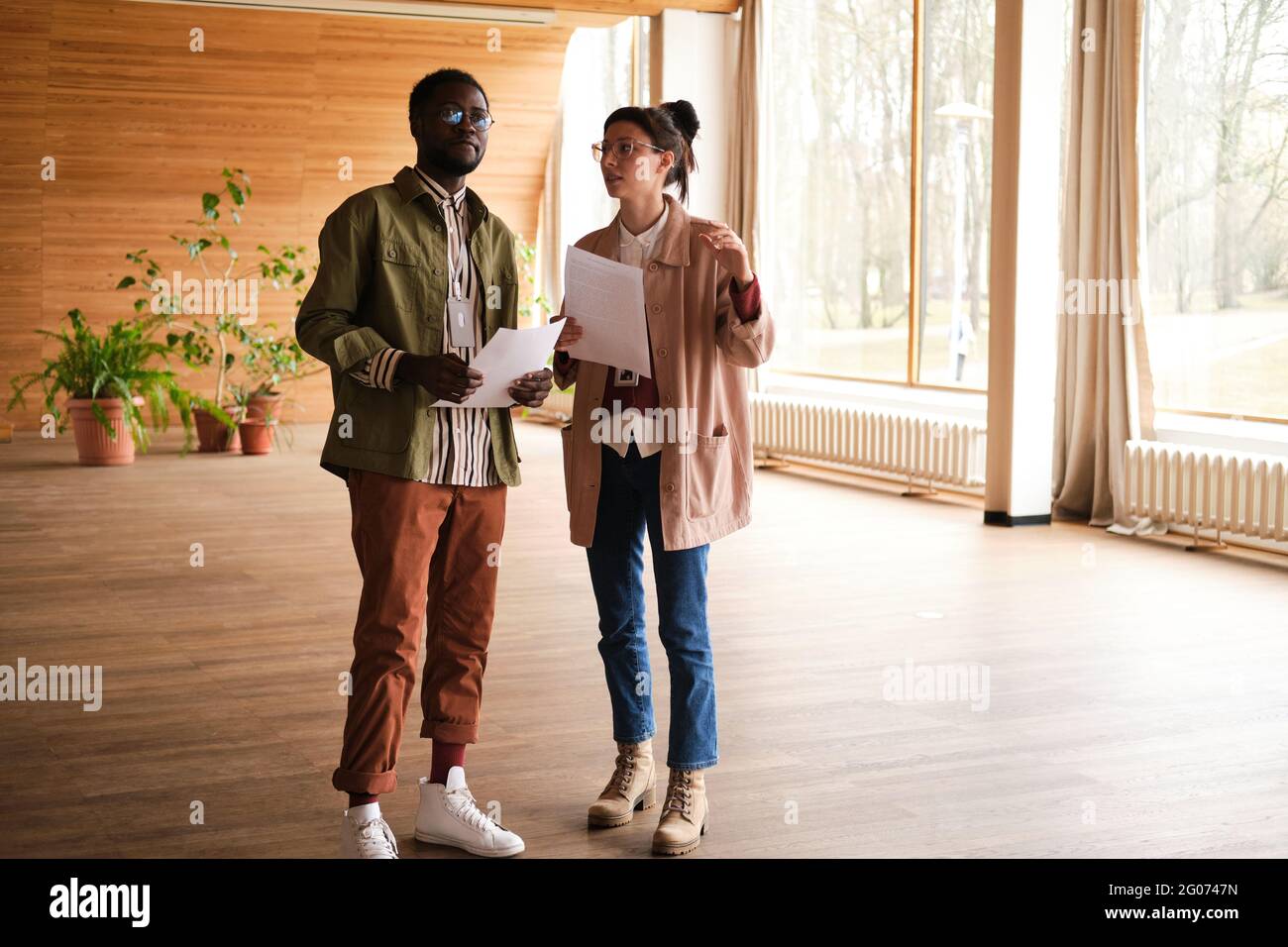 Two designers discussing project together while standing in empty room Stock Photo