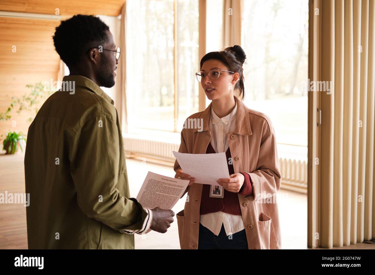 Two young designers with documents discussing future project together in team Stock Photo