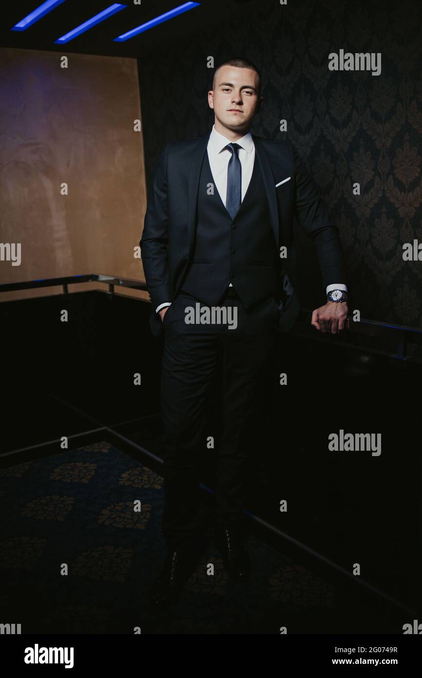 Young man in an elegant black suit with a tie posing Stock Photo - Alamy