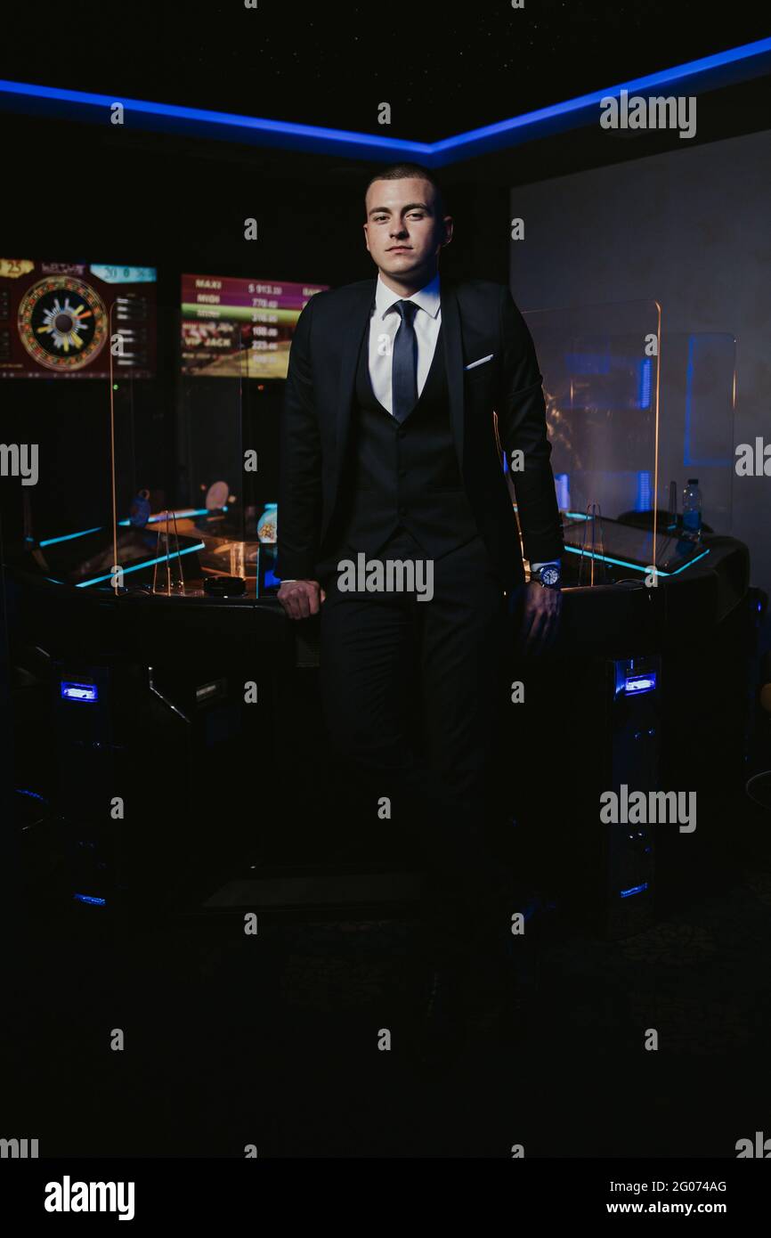 Young man in an elegant black suit with a tie posing in the casin Stock ...