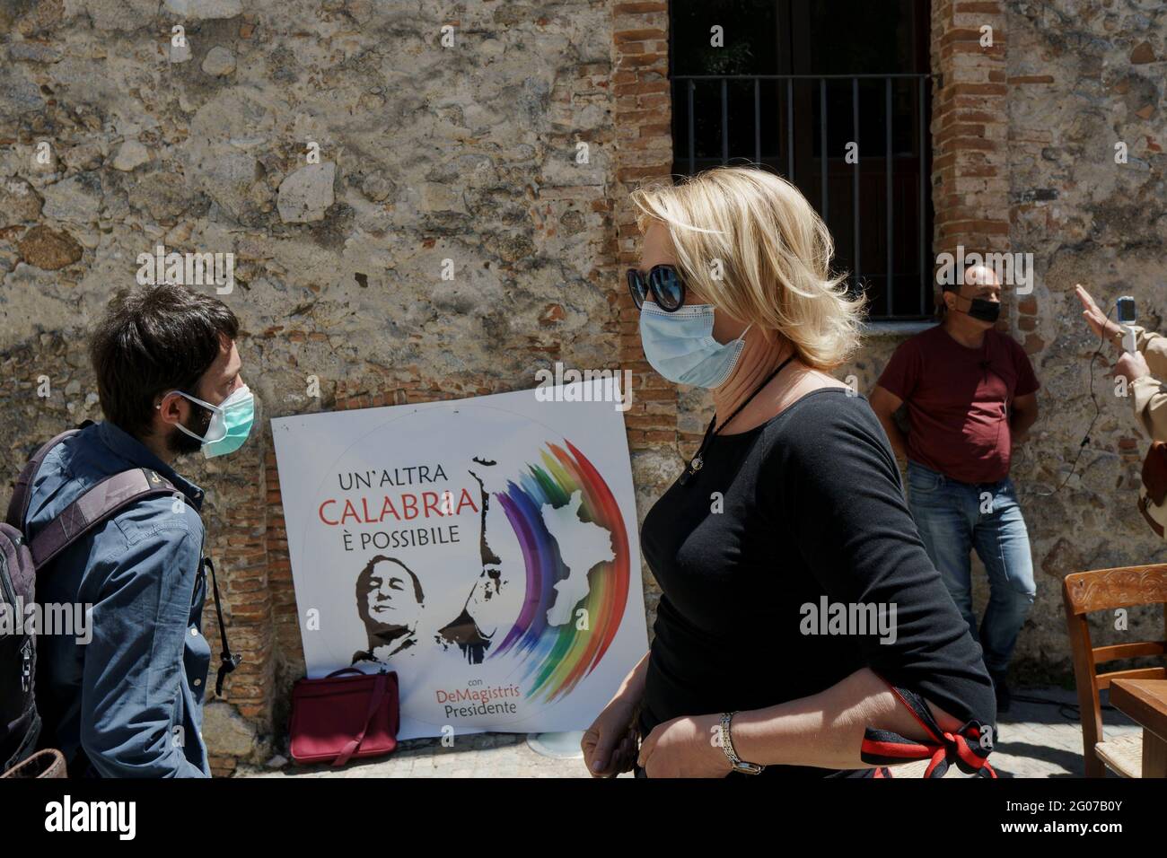 A woman passing by the banner with the new list's logo, during the press conference.Domenico Lucano “Mimmo”, former pro-migrant mayor of Riace, presented the electoral list “Un’Altra Calabria è possibile” (Another Calabria is possible) for the 2021 Calabrian regional election during a press conference hosted by Journalist Pietro Melia close to the local restaurant 'Taverna Donna Rosa'. The list will support the candidature of the mayor of Napoli, Luigi de Magistris, as Calabria Region’s Governor. Stock Photo