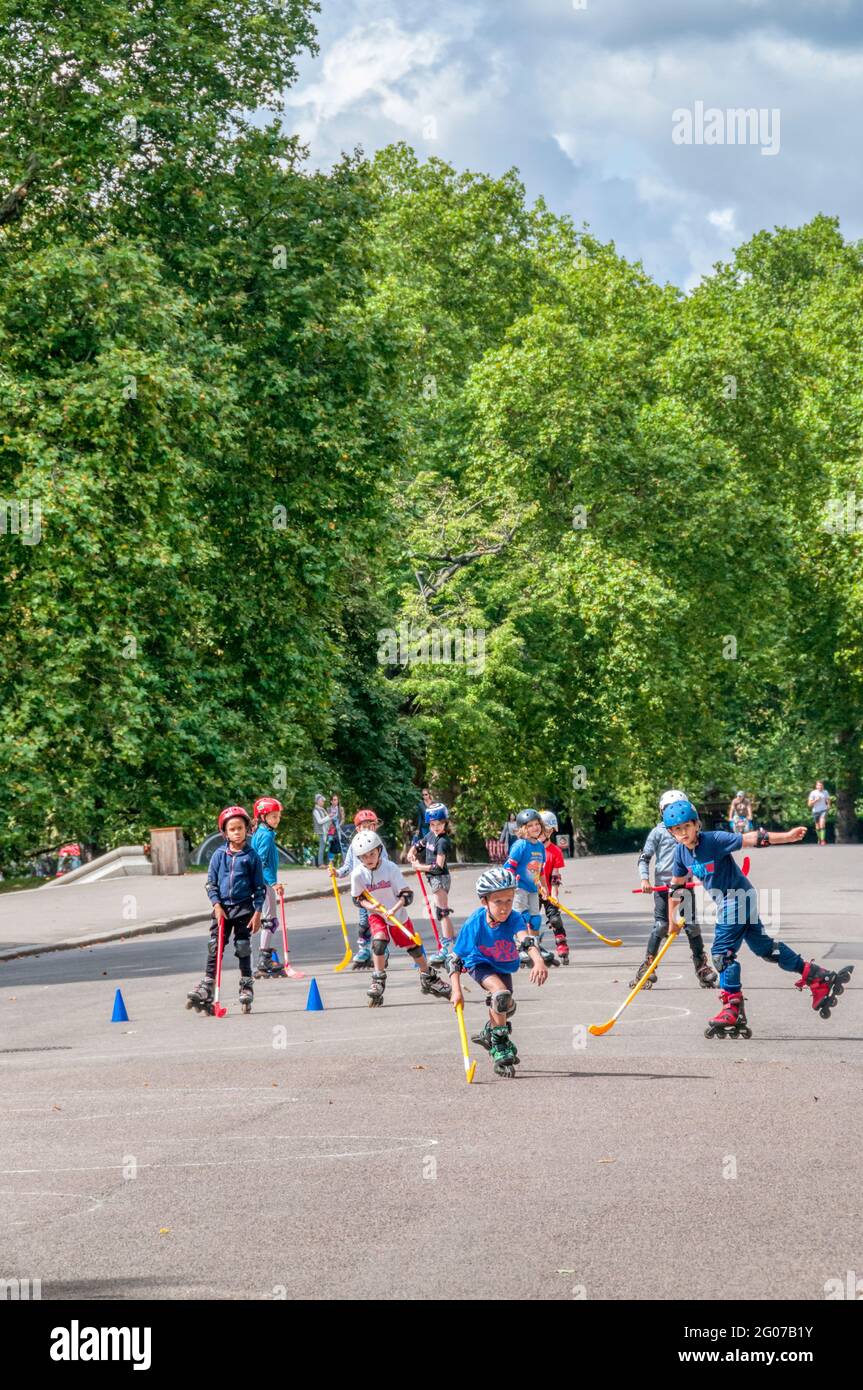 Children playing rollerblade hockey in Kensington Gardens, London. Stock Photo