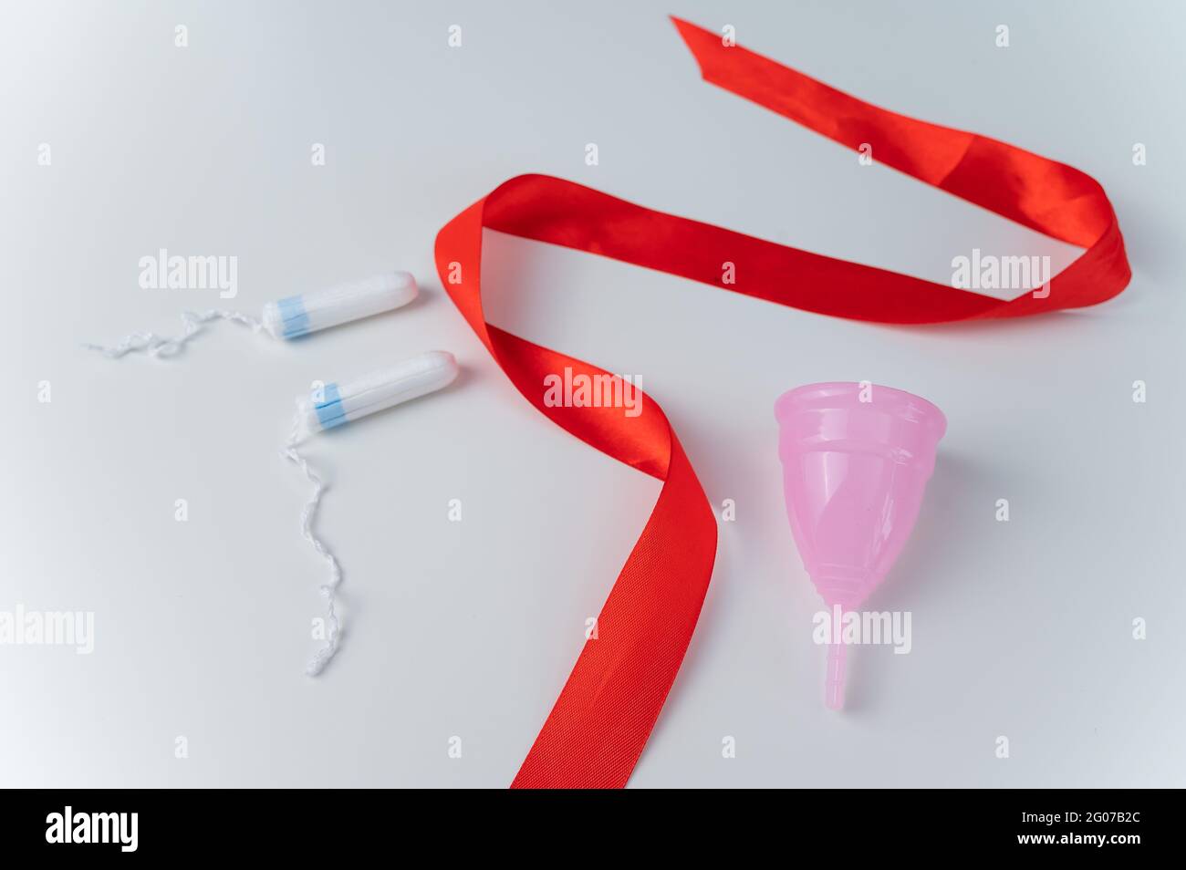 Tampon, pink menstrual cup and red satin ribbon on a white background.  Means of intimate hygiene of a woman during mentruation Stock Photo - Alamy
