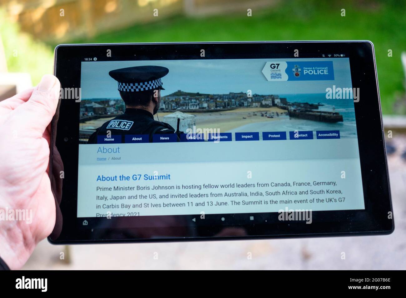 Man holding a tablet showing the Devon and Cornwall Police G7 information page. Stock Photo