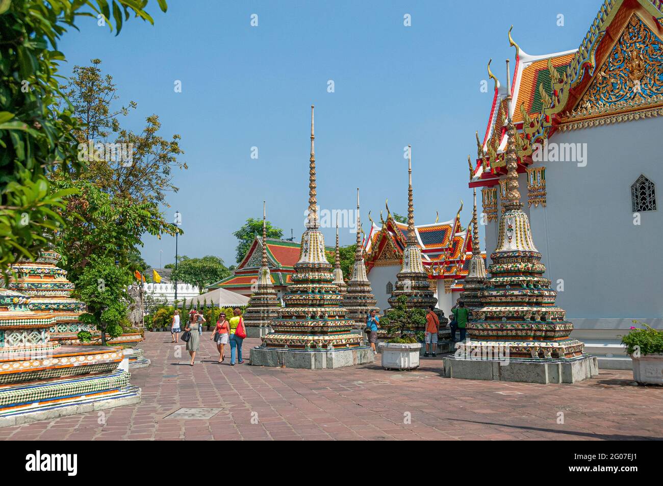 Tourists walking around ornate colourful prangs in the Wat Pho Wat Po Buddhist temple in Bangkok in Thailand in South East Asia. Stock Photo