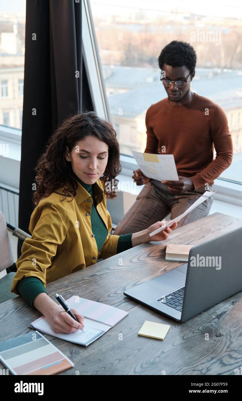 Two colleagues using documents and computer in their work they preparing for presentation at office Stock Photo
