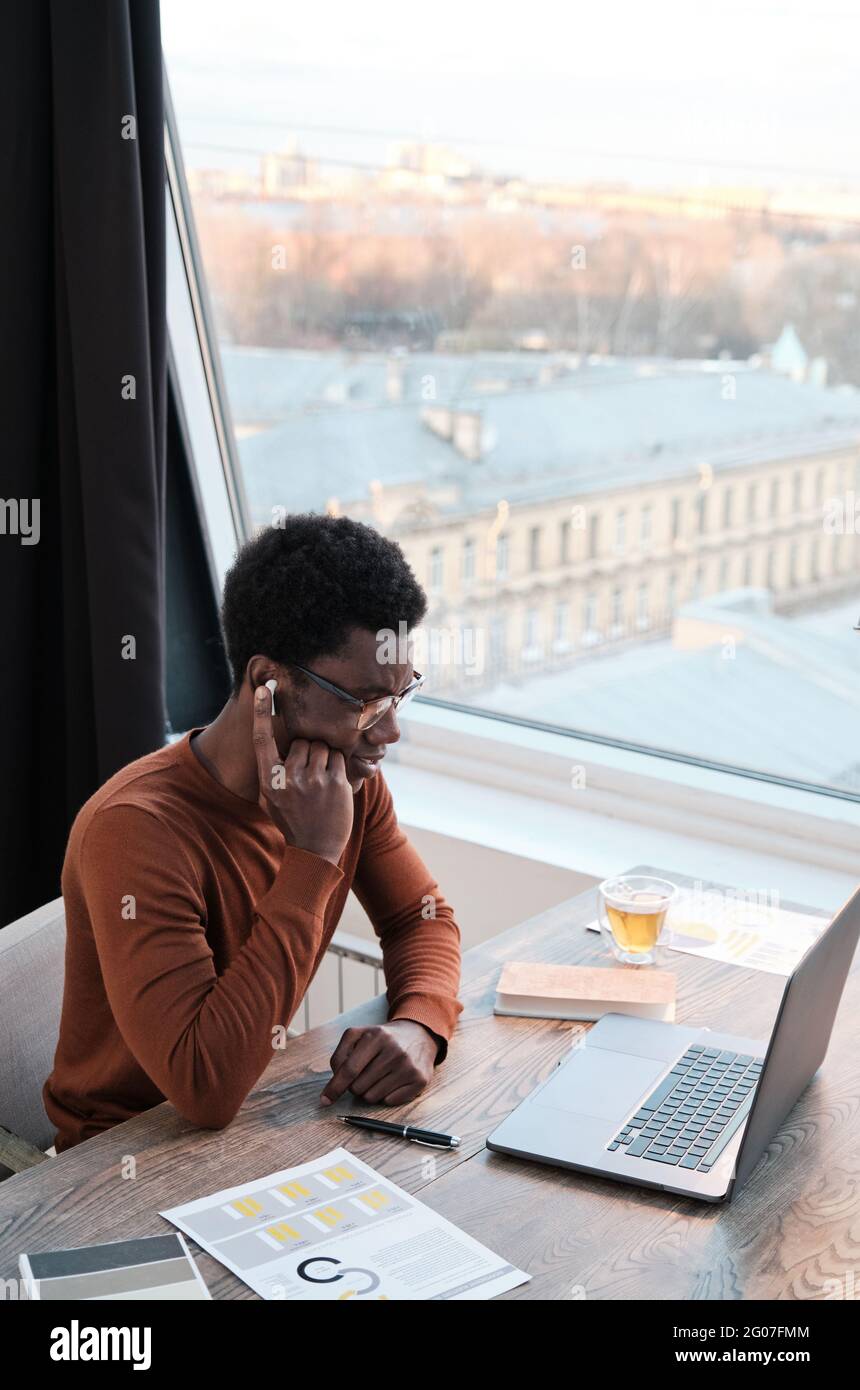 African man in headphones using computer for online conversation while working at office Stock Photo
