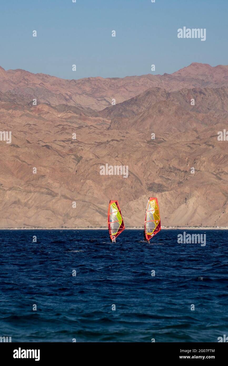 Eilat, Israel - May 24th, 2021: Two wind surfers off the shore of Eilat, Israel, with the jordanian Edom mountains in the hazy background. Stock Photo