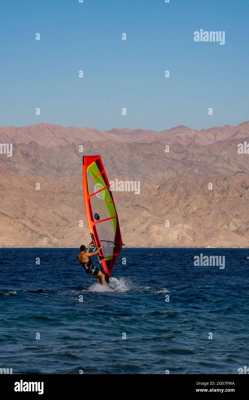 Eilat, Israel - May 24th, 2021: A man windsurfing off the shore of Eilat, Israel, with the jordanian Edom mountains in the hazy background. Stock Photo