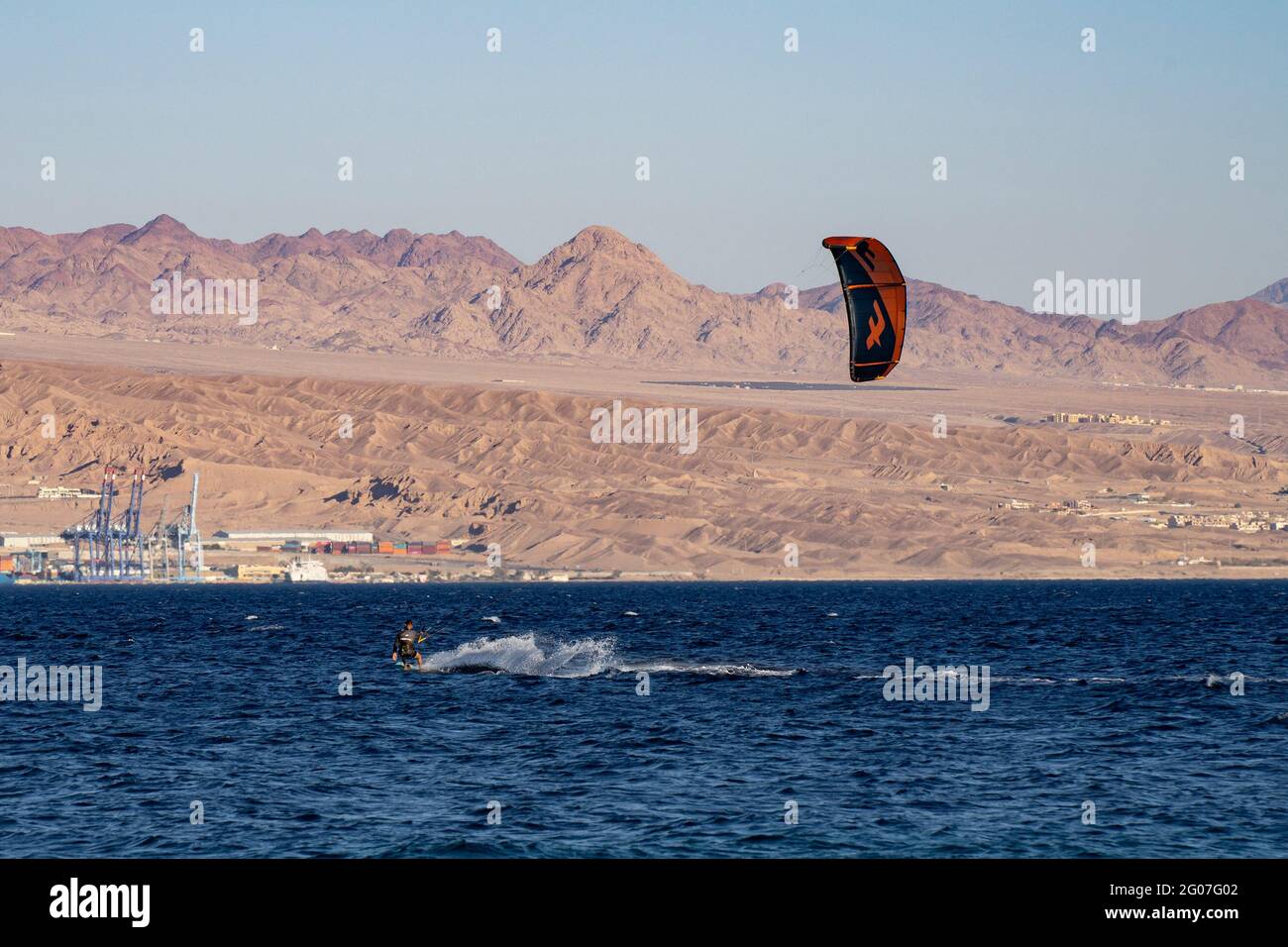 Eilat, Israel - May 24th, 2021: A man kite surfing off the shore of Eilat, Israel, with the jordanian Edom mountains in the hazy background. Stock Photo