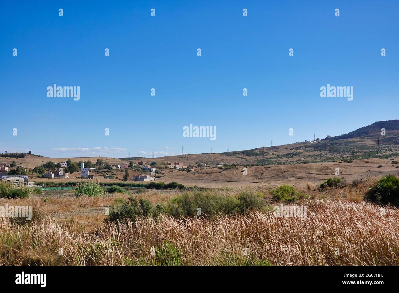 Grassy mountain field with village houses Stock Photo - Alamy