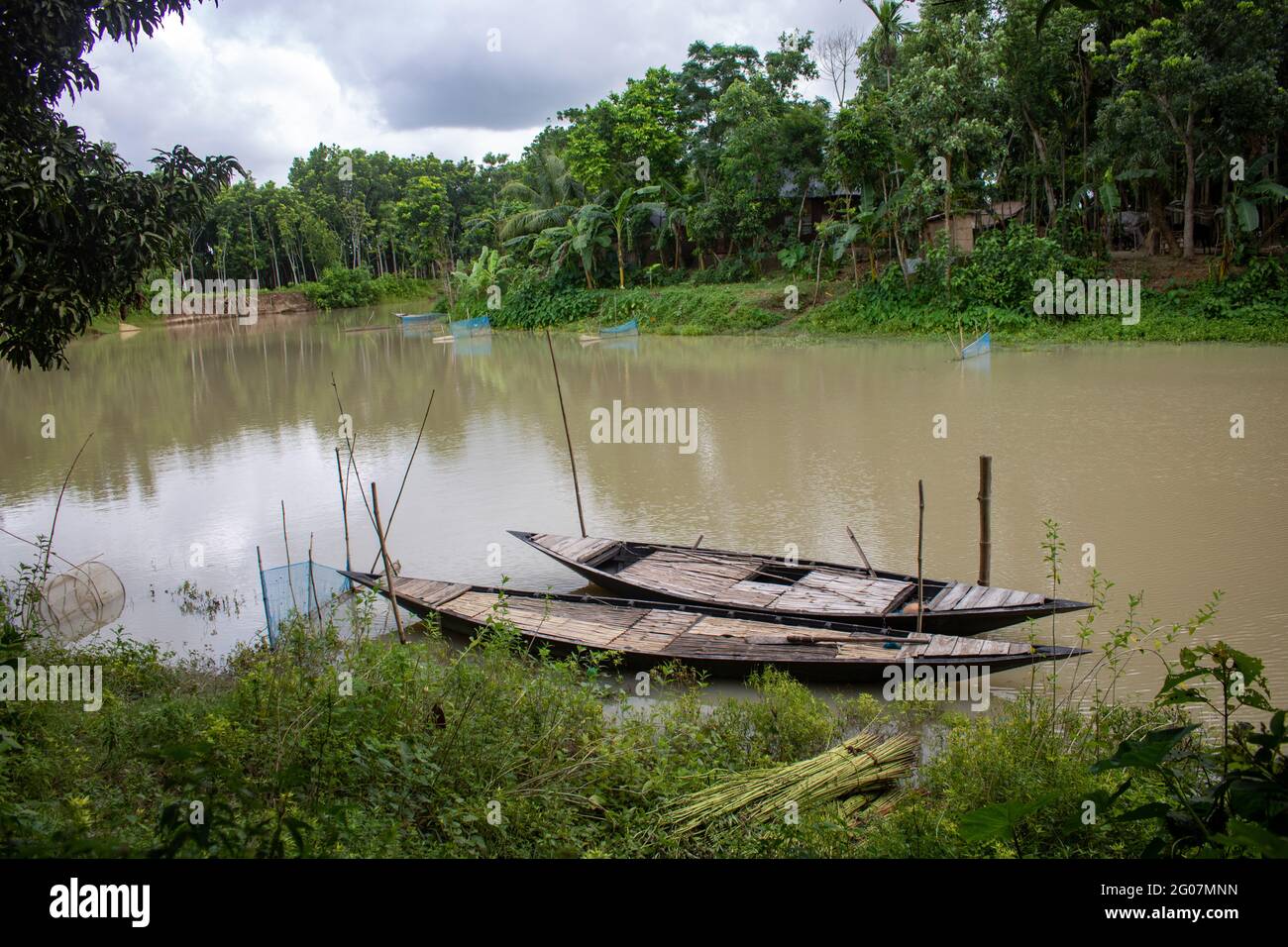 Bangladesh is a riverine country. A quiet beautiful small river. There are two boats tied up at the wharf. Stock Photo