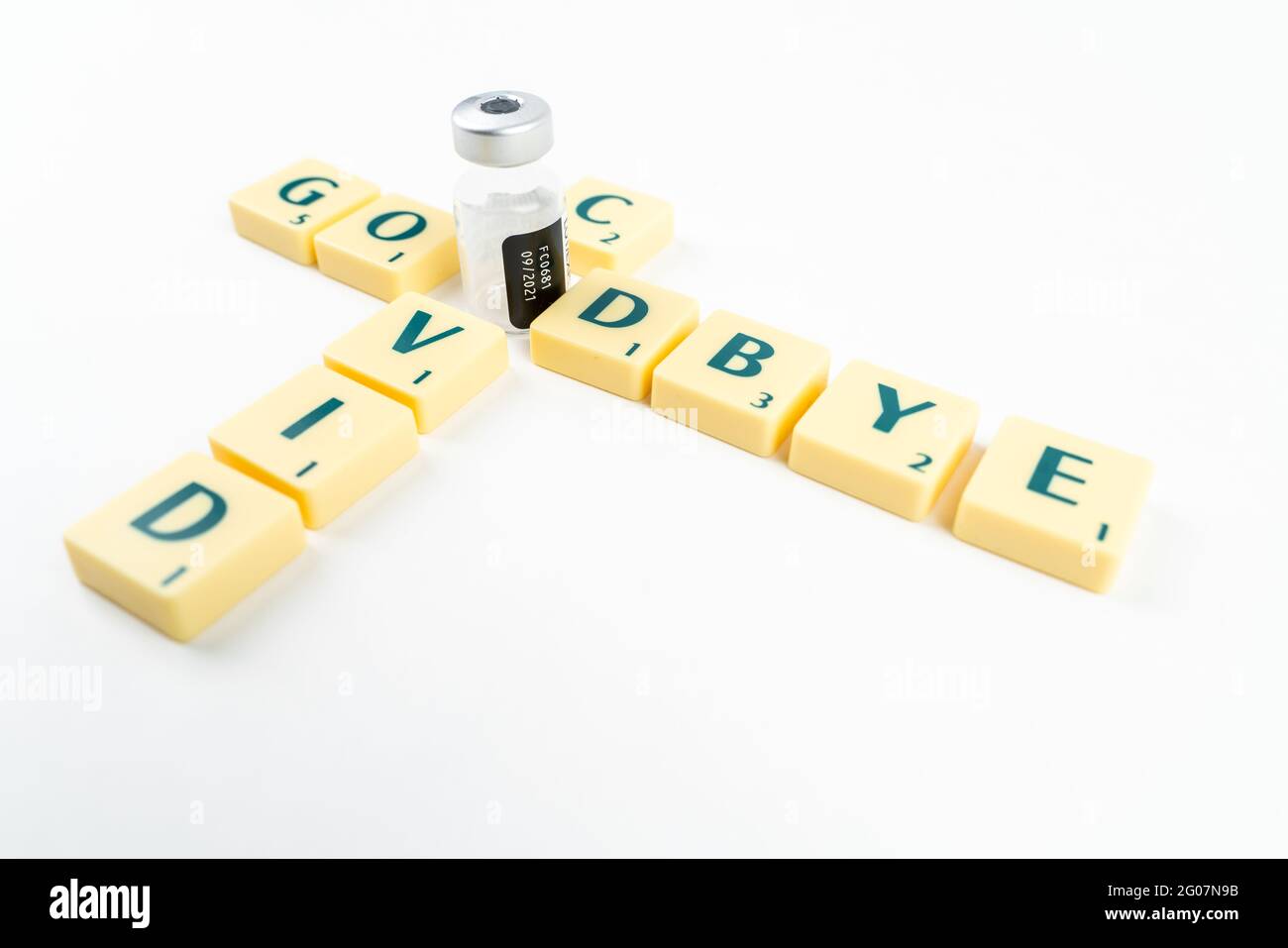 Yellow Scrabble letters saying GOODBYE COVID with the O letter replaced by vaccine ampoule. Ending the pandemic. Vaccination program. Covid-19 resolut Stock Photo