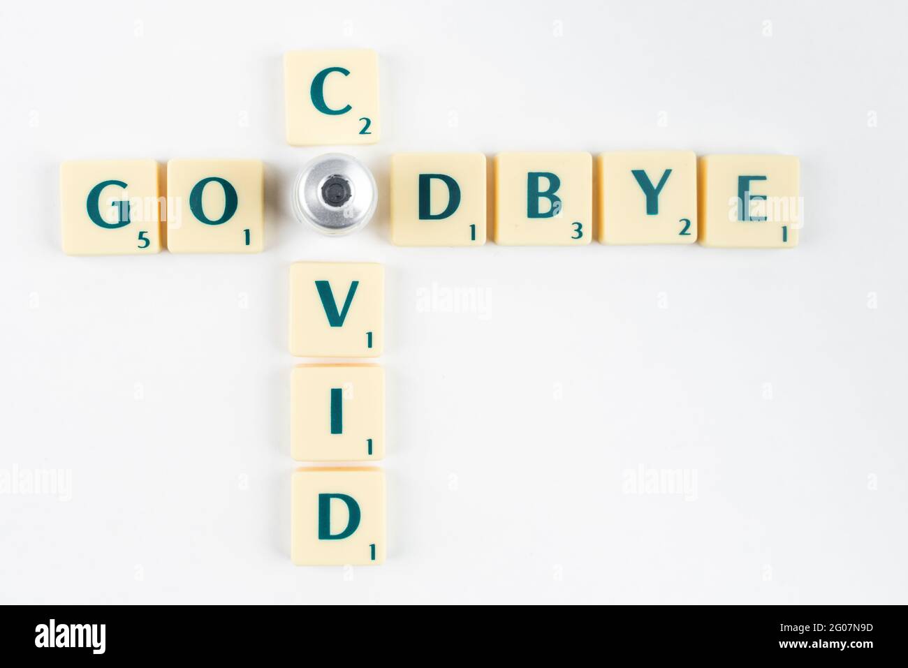 Yellow Scrabble letters saying GOODBYE COVID with the O letter replaced by vaccine ampoule. Ending the pandemic. Vaccination program. Covid-19 resolut Stock Photo