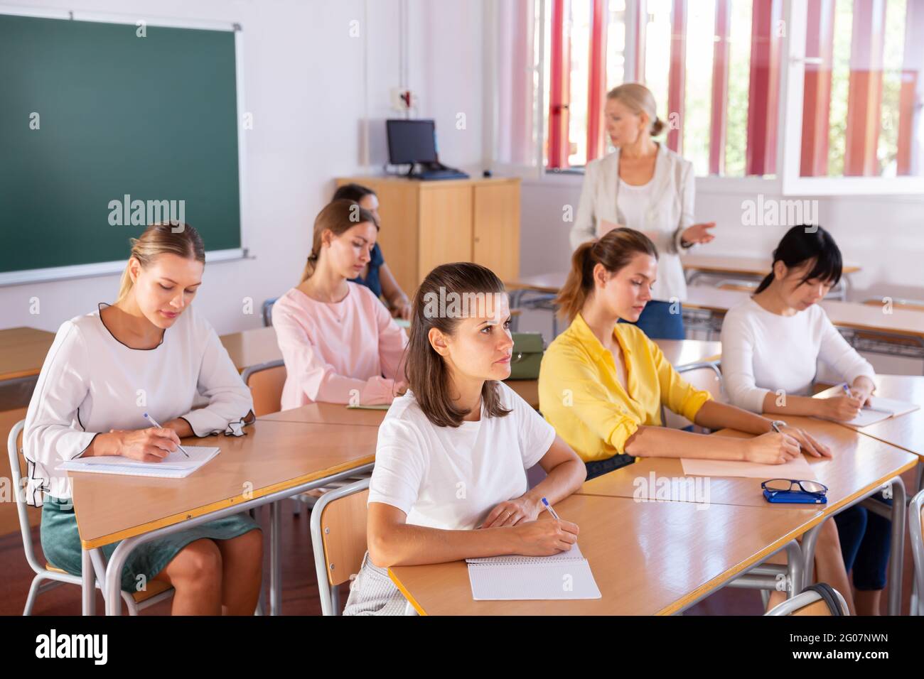 Students writing in notepads during lesson Stock Photo