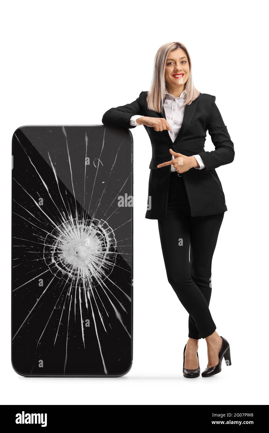 Full length portrait of a businesswoman leaning on a smartphone with a broken screen and pointing isolated on white background Stock Photo