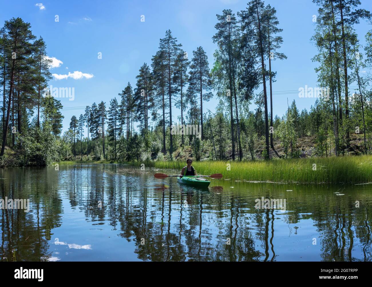 Middle age Caucasian Scandinavian women in kayak lifted the paddles and rests after kayaking in small river in forest. Northern Sweden, Tavelsjo lake, Stock Photo