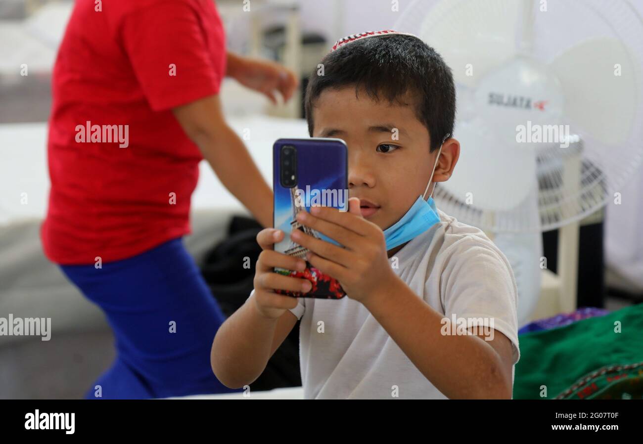 A covid-19 suspected patient, Jewish child from Manipur watching his mobile phone at the covid-19 care center.All 38 Jewish people from Manipur (State in Northeastern India) supposed to leave for Israel but could not catch the flight after being detected Covid-19 positive. The Guru Teg Bahadur covid-19 Care Centre has 400 beds with all facility equipped with essential oxygen support and medicine for the patient at free of cost only for those with an oxygen saturation level of 85 and above can be admitted, set up by Delhi Sikh Gurudwara Management Committee (DSGMC) with the help from Internatio Stock Photo