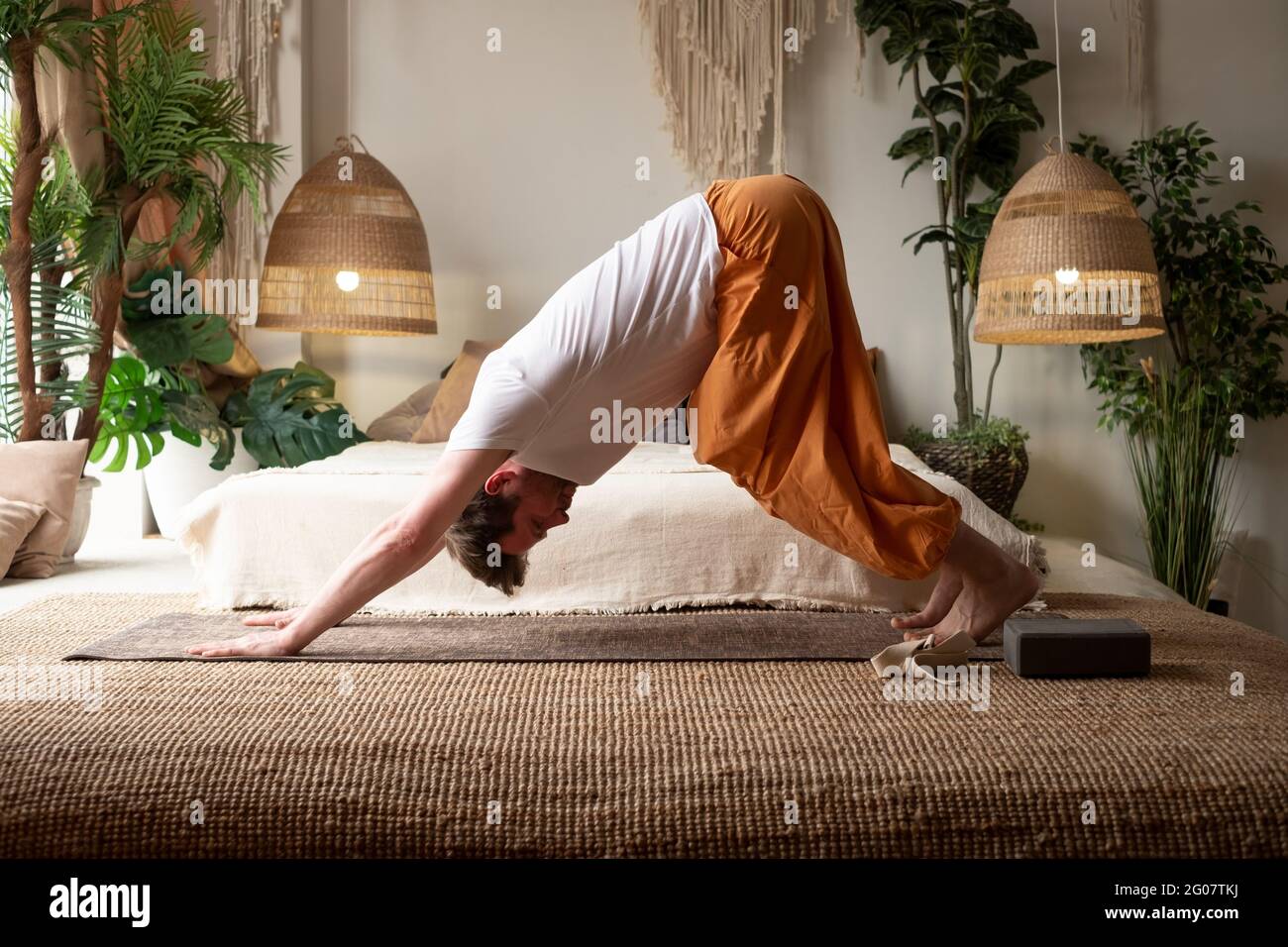Young man practicing yoga at home doing downward facing asana Stock Photo