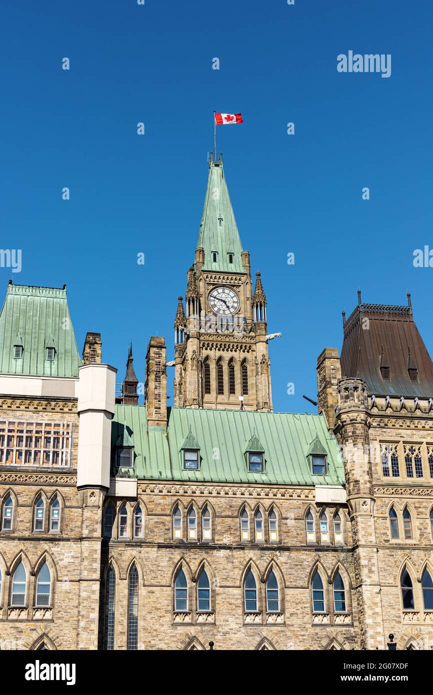 Ottawa, Canada - May 23, 2021: Parliament building with canadian flag in the capital of Canada, Ottawa against blue sky. Side view. Stock Photo