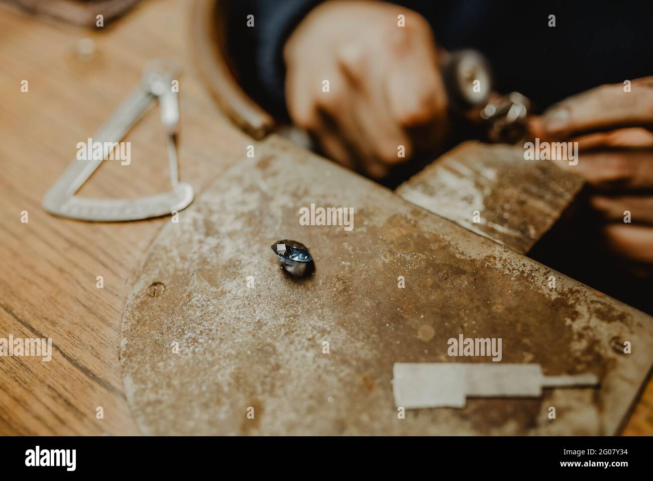 Jeweler using professional polishing machine on workbench while making