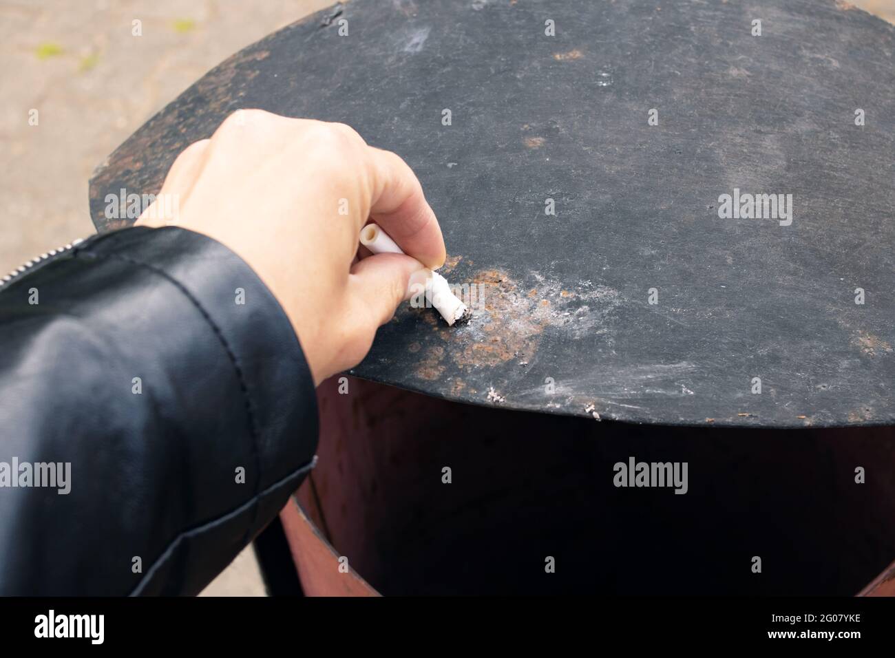 Hand extinguishes a cigarette on the trash can close up Stock Photo
