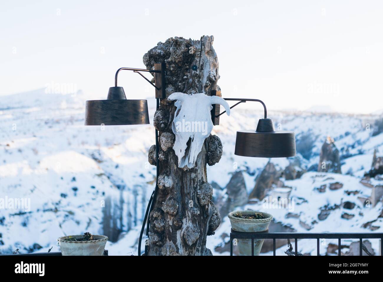 Aged rustic wooden streetlamps with animal skull against blurred snowy highland in sunny winter day Stock Photo