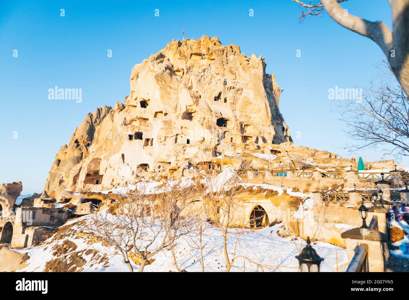 Low angle of aged castle carved in rock and covered with white snow against cloudless sky on street of Uchisar settlement in Cappadocia, Turkey Stock Photo