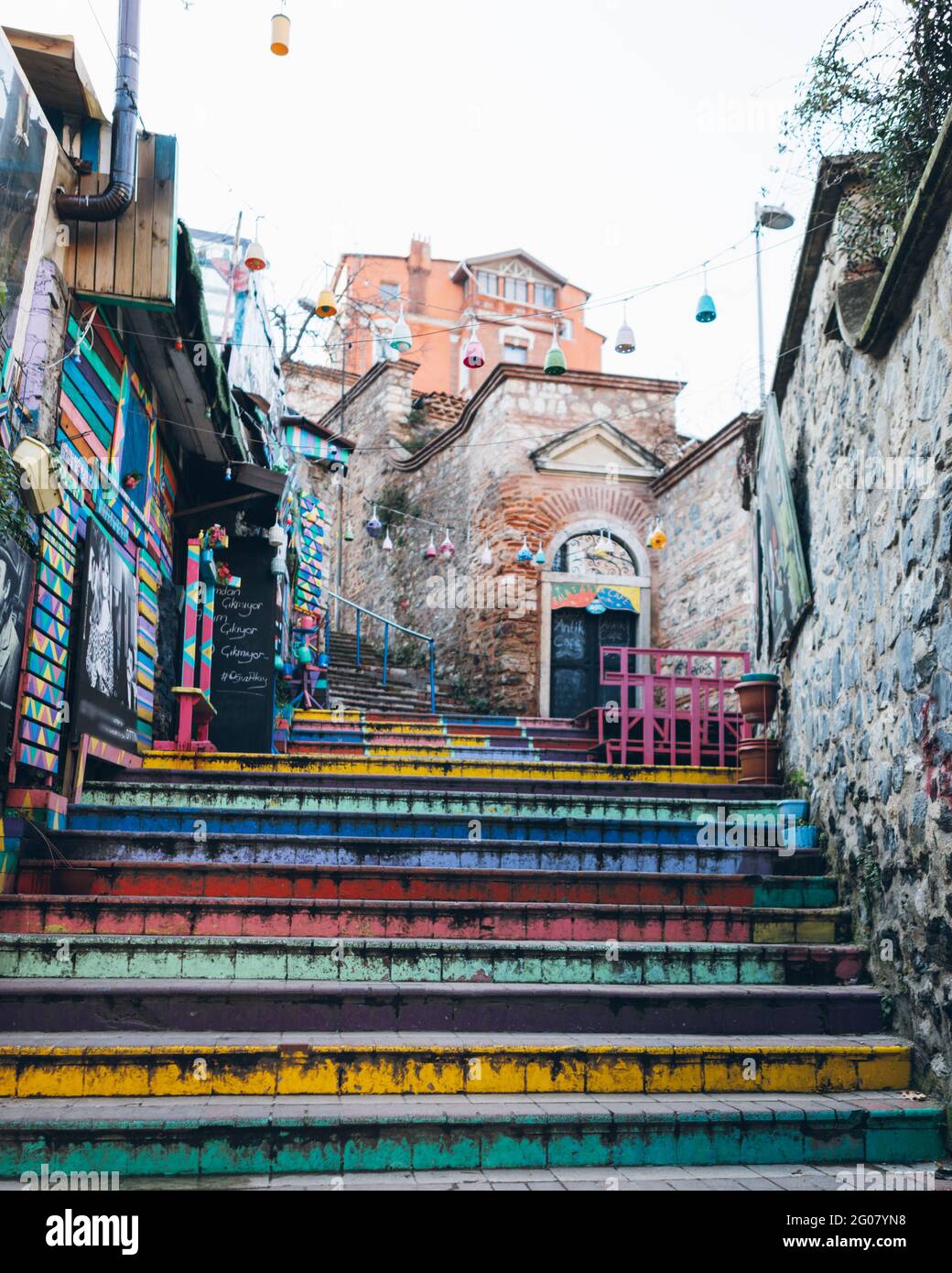 Shabby multicolored stairs under garlands near aged stone buildings on town street in Turkey Stock Photo