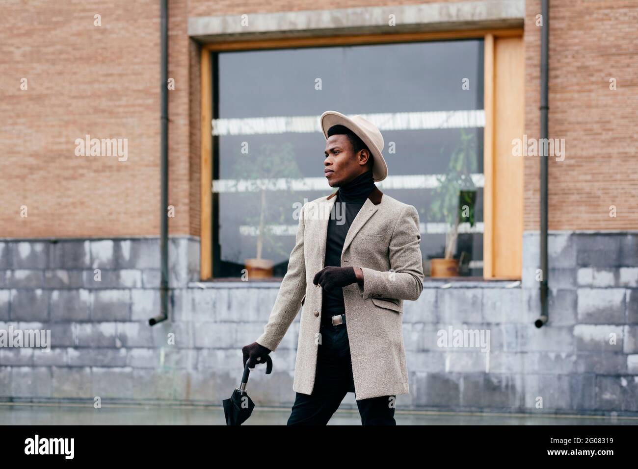 Portrait of elegant black man with grey coat in the street looking away Stock Photo